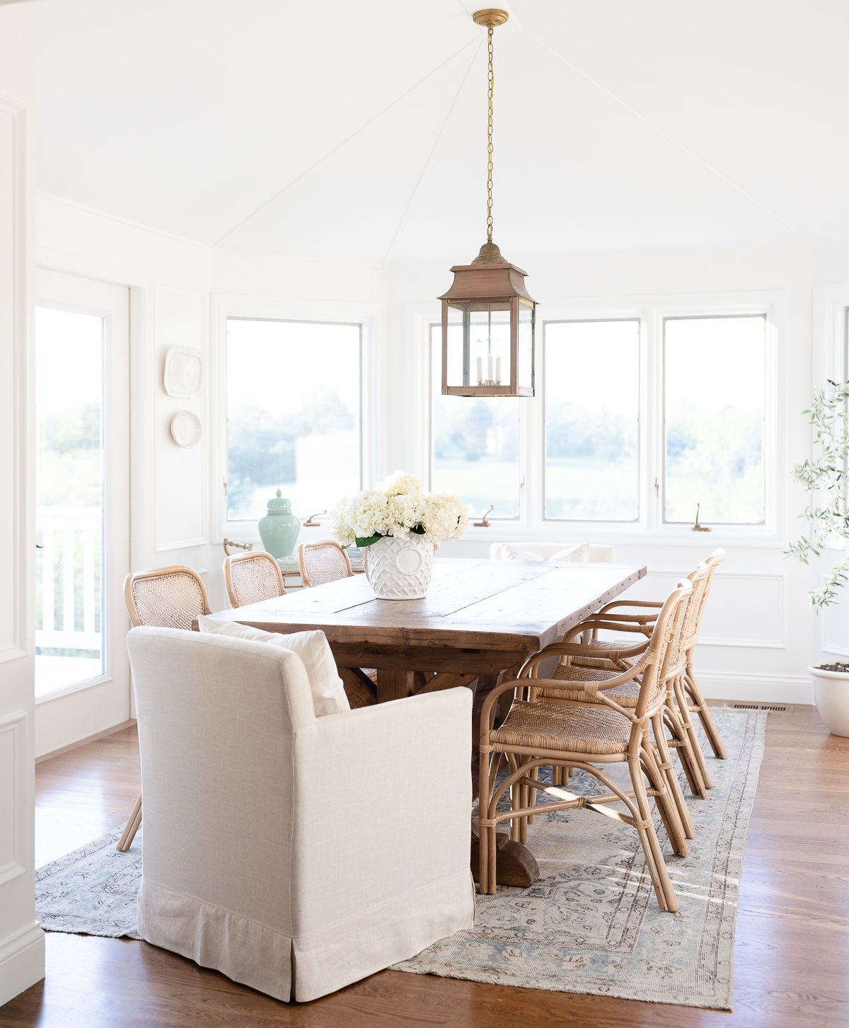 A white windowed breakfast nook with a wood dining table.