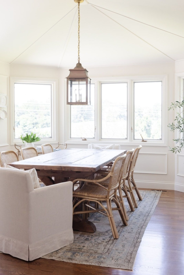 A casual dining room with cream walls and a cream color ceiling, with a wood dining table.