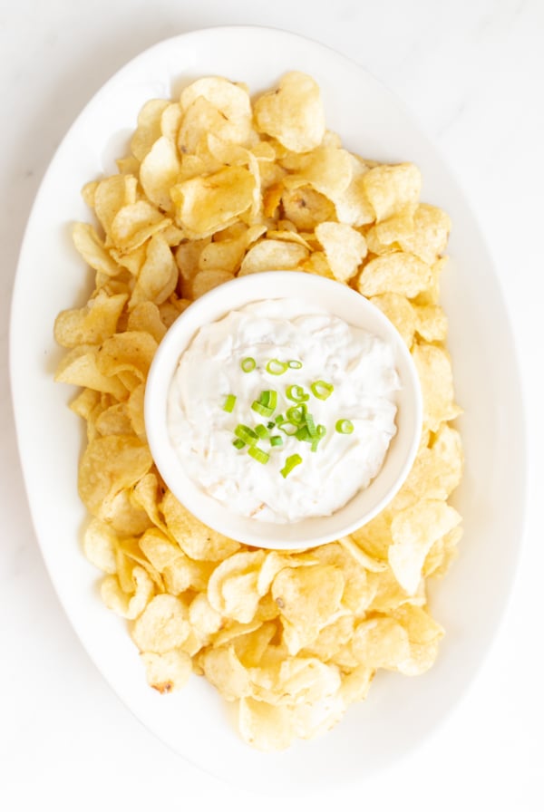 sour cream dip in a bowl surrounded by chips on a platter