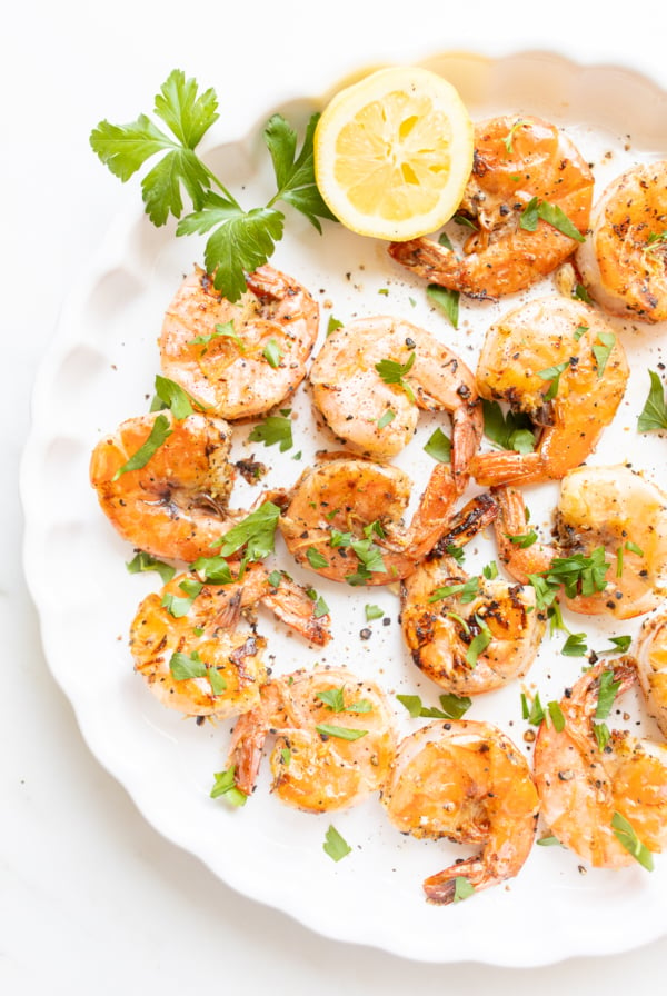 Lemon pepper shrimp on a round white serving platter.