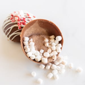 A peppermint hot chocolate bomb with marshmallows and sprinkles.