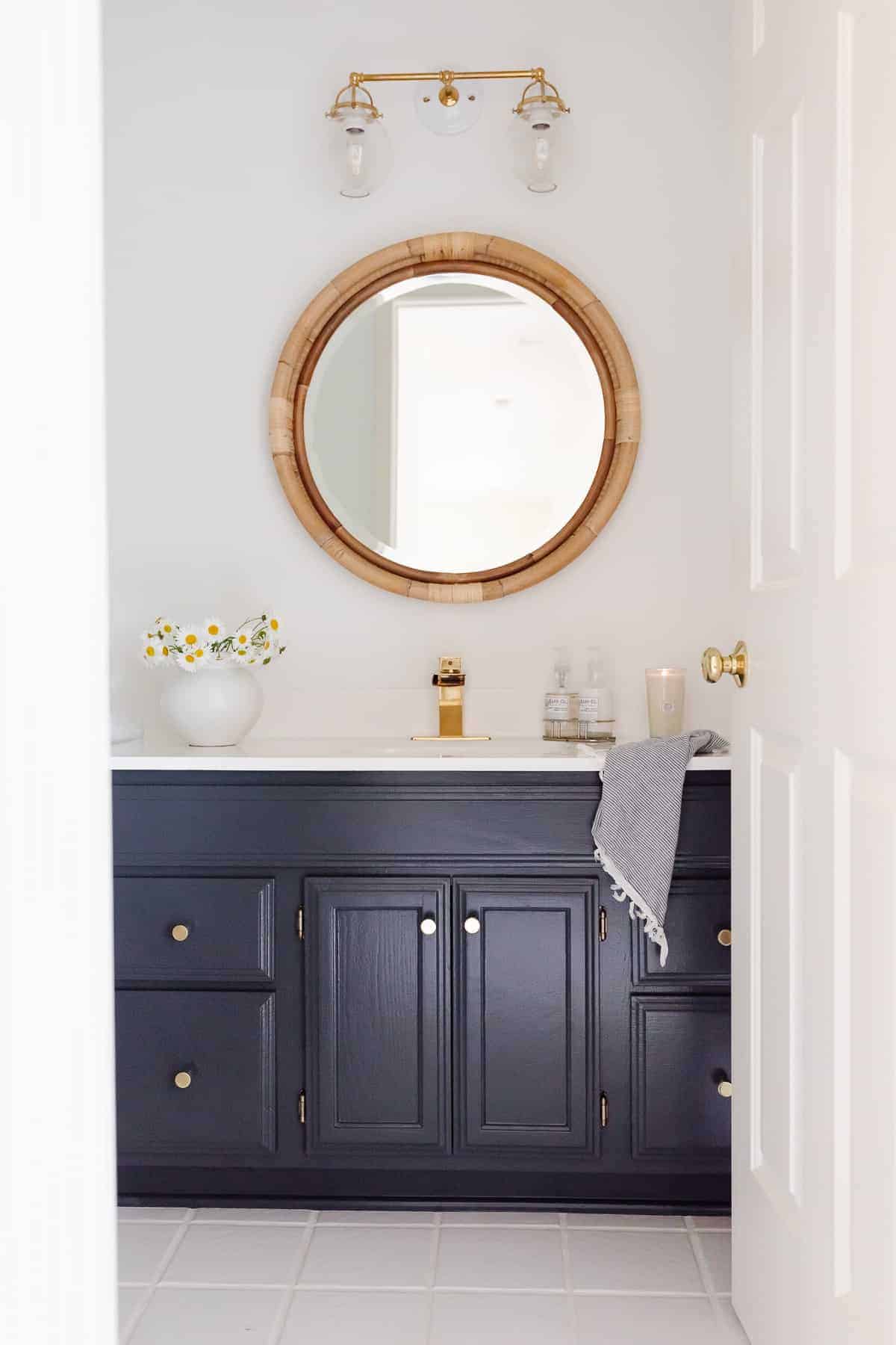 blue and white bathroom with rattan mirror and brass hardware