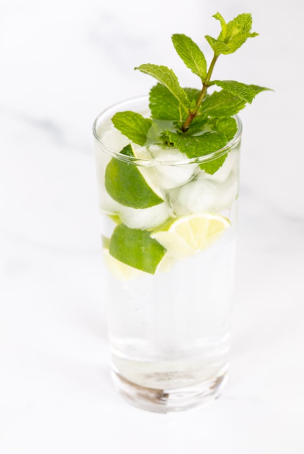 A clear glass full of a virgin mojito recipe on a marble surface.