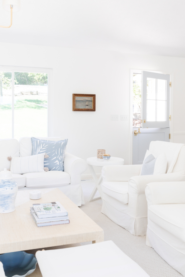 A white living room with blue accents, walls painted in Benjamin Moore Simply White.