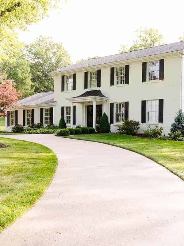 A colonial white brick house with a curved driveway.