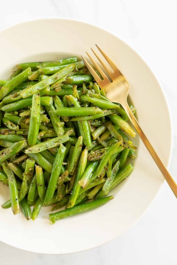 Seasoned green beans in a white bowl.