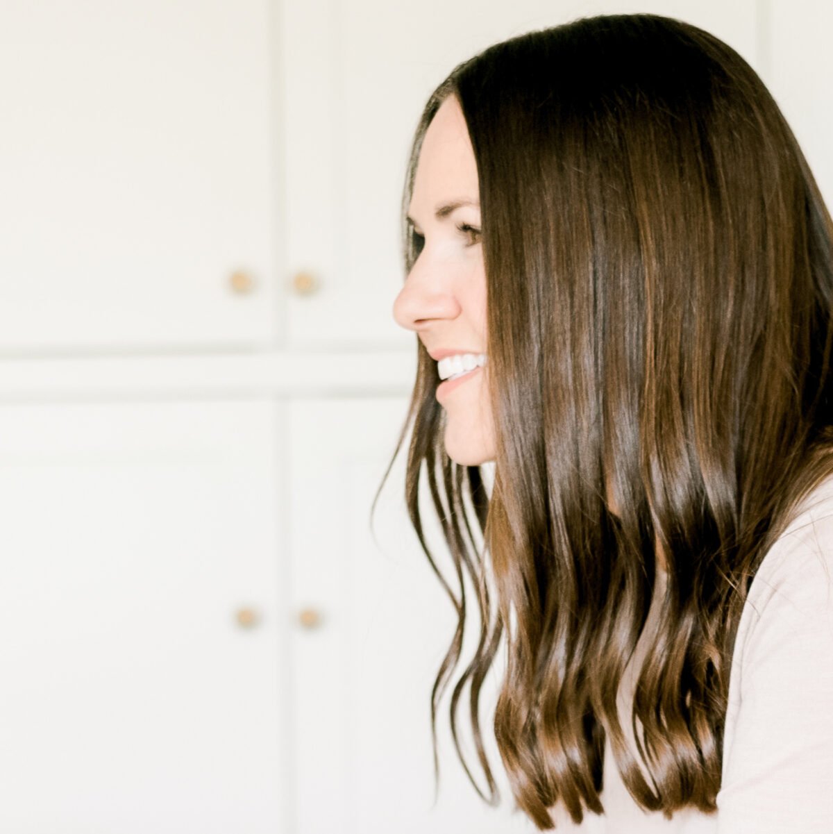 A woman with long brown hair is smiling at the camera.