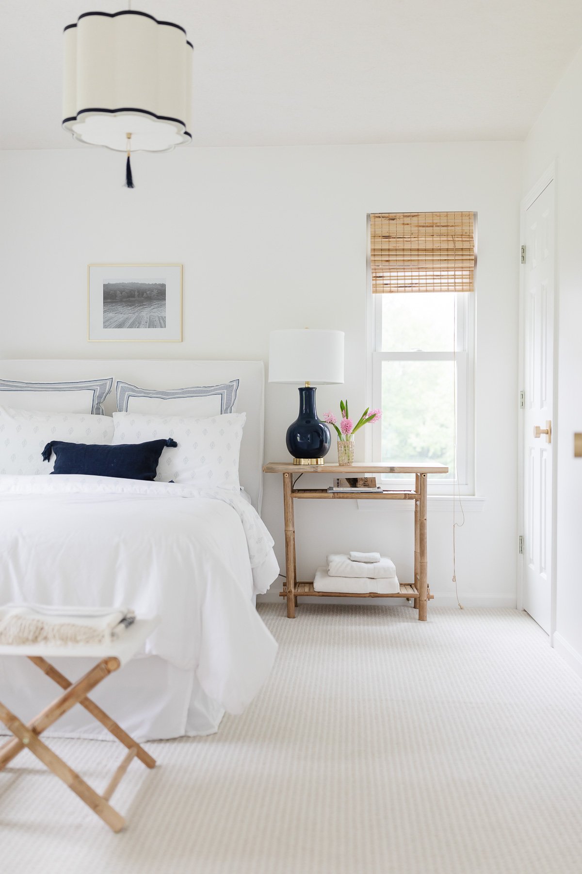 A white bedroom with a bed and a rug, decorated in lake house decor.