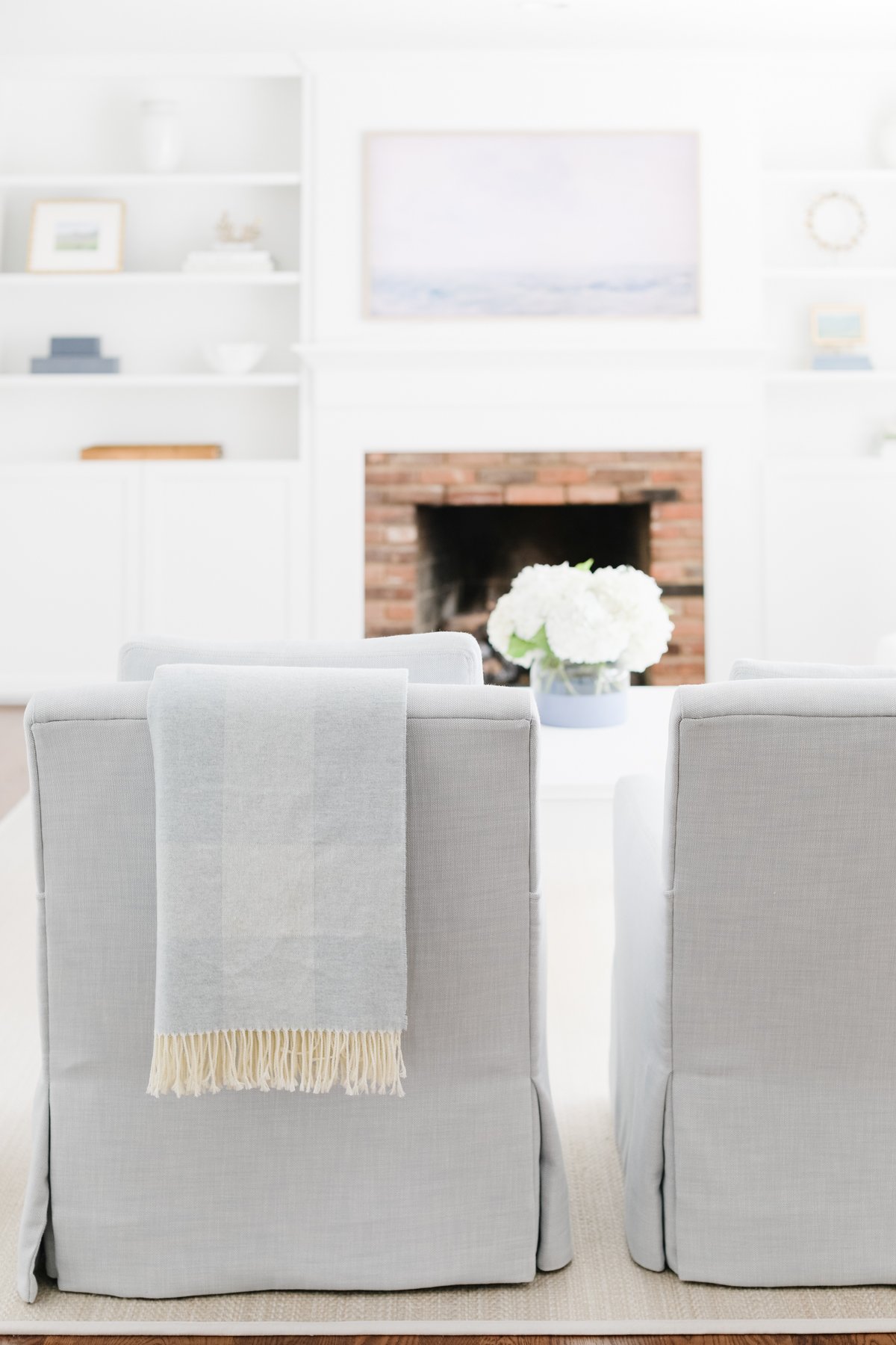 Two grey chairs in front of a fireplace embody the elegant Serena and Lily look for less in a living room.