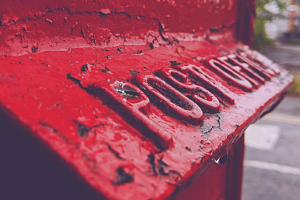 A close up of an old red postbox, showing the cast iron name "post office" on it.