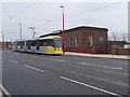 SJ9098 : Metrolink Tram passing Droylsden Library by David Dixon