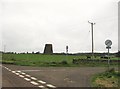 NX9783 : The remains of an old windmill beside a road junction by Ann Cook