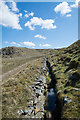 NY8635 : Stream in stone-lined channel by Trevor Littlewood