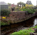 SS9379 : Yellow warning notice on a wall above a stream, Coychurch by Jaggery