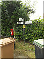 TL9769 : Stock Hill Postbox & Roadsign by Geographer