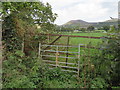 SJ1359 : A rusty gateway, a bench mark, and a view to the hills by John S Turner