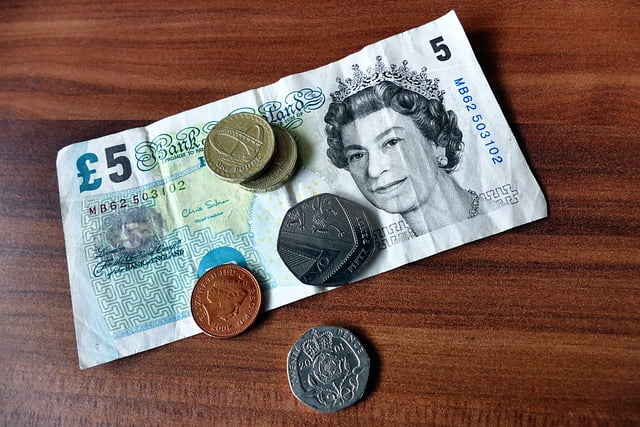 A fiver and some coins on a table.