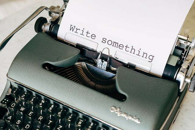 A typewriter. The words "Write something" are typed onto the fresh white paper.