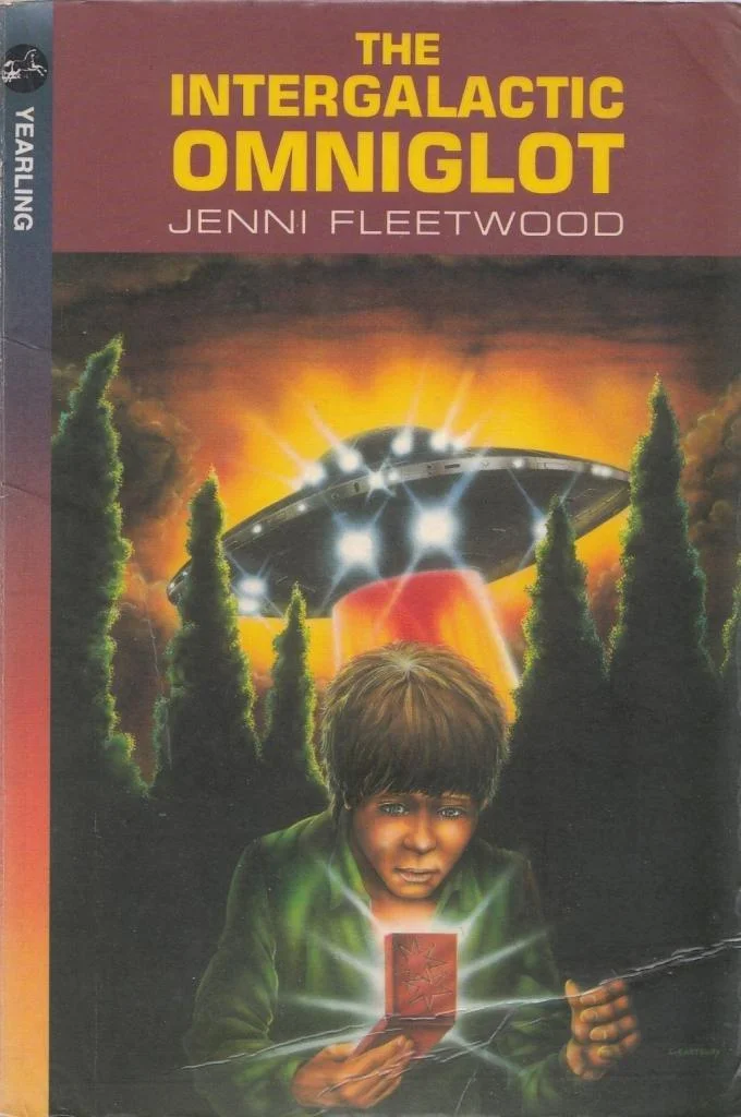 Paperback book cover. A UFO rises behind a young man. The Boy is holding what looks like a foldable Gameboy.