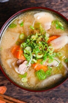 Japanese "Tonjiru" pork miso soup in a black and red bowl topped with shichimi togarashi (chili powder) and green onions