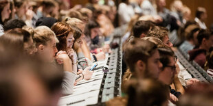 Seitenansicht von Studierenden, die in einem Hörsaal sitzen