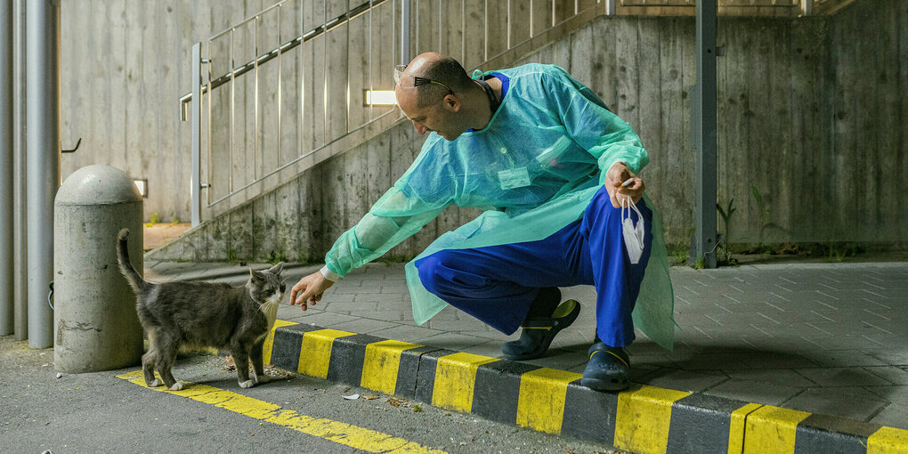 Ein Krankenpfleger streichelt eine Katze.