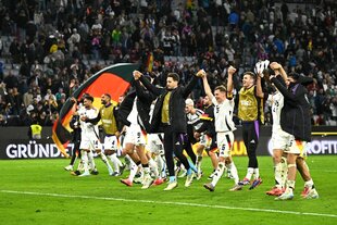 Die deutsche Fußballnationalmannschaft der Männer steht auf dem Stadionrasen und hält sich glücklich an den Händen