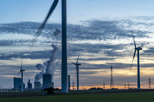 Ein Braunkohlekraftwerk und Windkrafträder in der Dämmerung