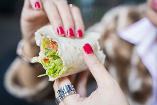 Eine Frau isst ein Wickel-Sandwich mit der Hand