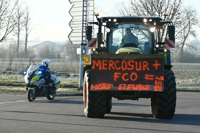 Ein Traktor und ein Polizeimotorrad stehen neben einander auf einer Straße