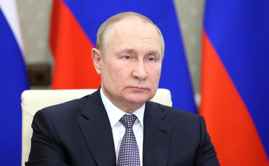 Russian President Vladimir Putin sitting at a table, with a serious expression