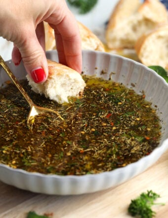 Hand dipping bread into garlic Parmesan oil