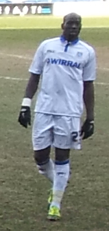 Montserratian professional footballer Donervon Joseph Daniels walking on pitch wearing a white uniform