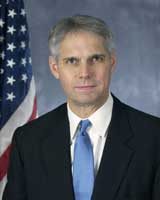 A portrait photo of Mark J Sullivan in front of a US flag