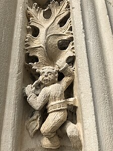 Sculpture d'un petit homme escaladant une feuille de vigne.