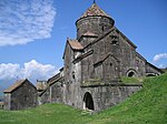 Small church of dark stone with a central tower topped by a conical roof.