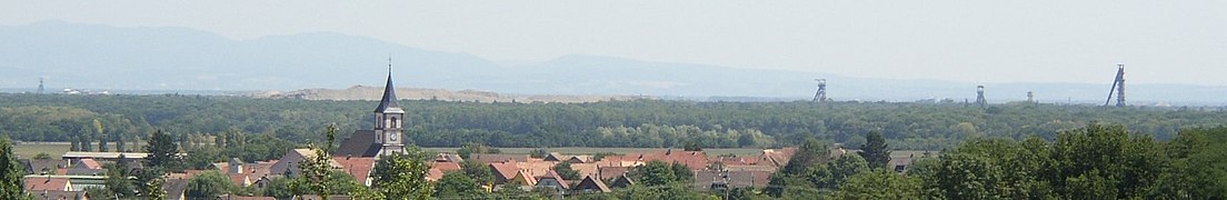 Paysage du bassin potassique vers l'an 2000, marqué par quatre chevalements et un long terril et dont les parties urbanisées alternent avec la forêt du Nonnenbruch.