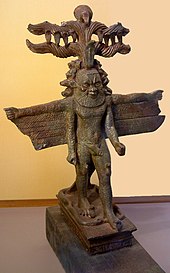 Bronze statue of a bearded man with multiple arms, wings, horns, and several animal heads emerging from the sides of his head