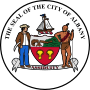 Circular seal with central images of a shield at center and sailing ship above it, with a European man to the left and a Native American to the right. The seal's edge reads "THE SEAL OF THE CITY OF ALBANY" with "ASSIDUITY" in a banner above the bottom.