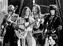 Eric Clapton, John Lennon, Mitch Mitchell und Keith Richards eng bei einander stehend im Jahr 1968 . Aufnahme von vorn mit Gitarren und anderen Instrumenten in der Hand und offenbar ein Konzert gebend in schwarzweiß.