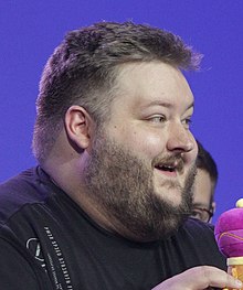 Un homme aux cheveux et à la barbe brune, vu de profil.