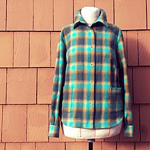 Grenn flannel shirt in front of red brick wall