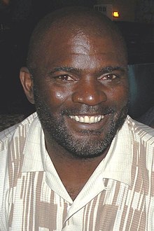 An American football player looking at the camera while wearing a blazer.