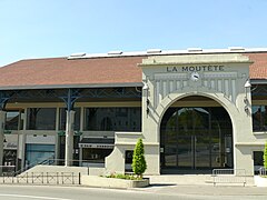 Vue d'un bâtiment vitré avec une grande porte en pierre.