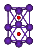 The ball-and-stick diagram shows two regular octahedra which are connected to each other by one face. All nine vertices of the structure are purple spheres representing rubidium, and at the centre of each octahedron is a small red sphere representing oxygen.