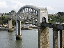 a bridge spanning a river at high level, the bridge deck supported in the centre by curved tubular metal girders