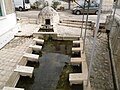 La fontaine avec son dôme en pierre et son lavoir.