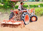 Jordfräs, kopplad till en traktor under arbete med att preparera ett thailändskt risfält.