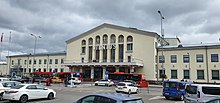 A large, white building, seen from a parking lot