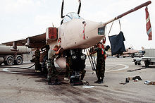 View of mechanics servicing a desert pink jet aircraft.